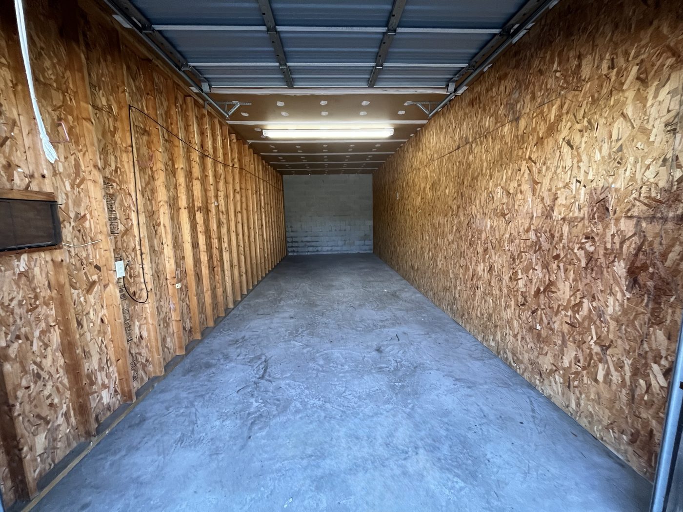 Interior of a warehouse unit showing concrete floor, lighting, and depth